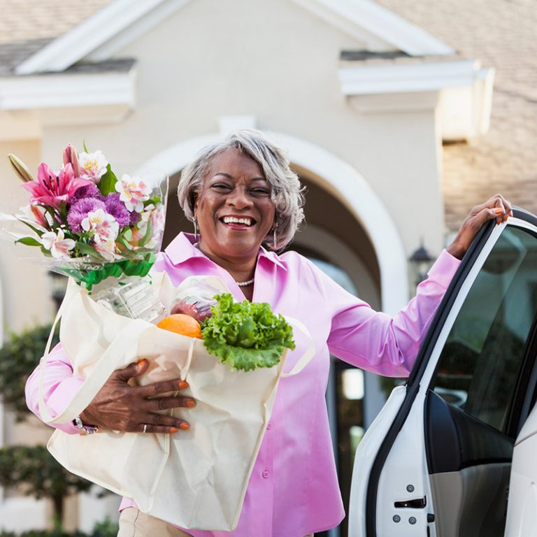 Woman holding flowers and smiling near a car